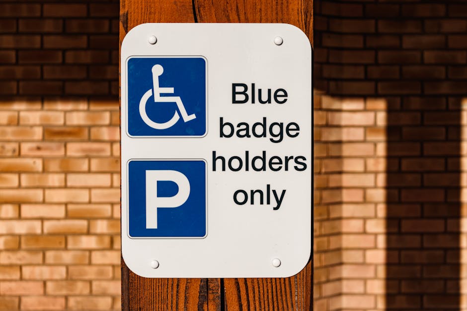 A close-up of a rectangular white parking restriction sign with a black border, mounted on a metal pole against a clear blue sky. The sign displays a large red circle with a diagonal line crossing out